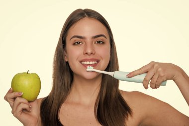 Beyaz tenli dişlek kadın gülüşü. Dişlerini elektrikli diş fırçasıyla fırçalayan bir kadın. Dişlerini fırçalayan bir kız. Beyaz dişler. Diş sağlığı kliniği. Elektrikli diş fırçası. Yumuşak Tüylü Diş Fırçası.