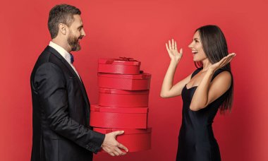 Sevgililer Günü. Çift Sevgililer Günü 'ne hediye veriyor. Erkek ve kadının hediyeleri var. Kırmızıda zarif bir çift. Hediye değişimi. Birlikte romantik bir gün. Yıldönümü için aşk hediyesi. Karşılıklı sürpriz..