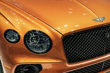 New York City, ABD - 27 Mart 2024: Bentley Continental GT lüks araba farları ve New York Uluslararası Otomobil Fuarı logosu, yakın görüş.