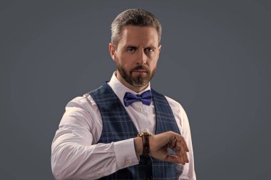 Dakik adam gri üzerinde izole zamanı kontrol ediyor. Erkek aksesuarı. Papyonlu beyefendi toplantıya geç kaldı. Zaman yönetimi. Dakik adam, nöbete geç kalma zamanını kontrol ediyor. Zarif saat aksesuarı.