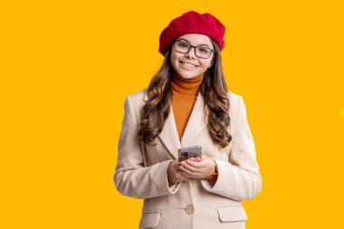Kız genel olarak telefonda konuşuyor. Ergenlik çağı z, telefonu olan ergenlik çağındaki kız öğrenci. İletişim. Düşen kız sarıda izole edilmiş bir telefon kullanıyor. Sonbahar tarzı ceketli bir genç. Sonbahar biçimi.