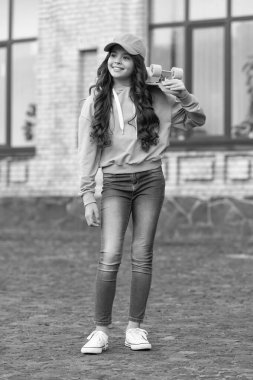 childhood of teen girl skater smile outdoor. childhood of teen girl skater outside. childhood of teen girl skater at the street. childhood of teen girl skater with skateboard.