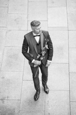engagement date. caucasian tuxedo man celebrates engagement. man with rose gift for engagement.