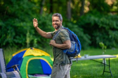 Ormanda çadırlı sırt çantalı bir adam. Yaz günü doğa yürüyüşçüsü. Yaz kampı ve doğa tatili. Yaz kampındaki adam. Kamp macerası. Yürüyüş konsepti. Kamp çadırı. Merhaba..