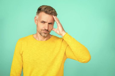 Baş ağrısı ve migren. Olgun adam baş ağrısından muzdarip. Baş ağrısı ve stresi olan bir adam. Adam acıdan yoruldu. Kafkasyalı bir adam mavilikte migren olduğunu düşünüyor. Boşluğu kopyala.