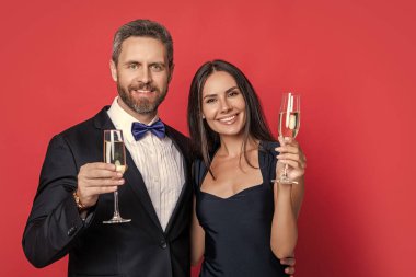 Romantik randevu kutlamaları. Sevgililer Günü. Yıldönümünü kutlayalım. Aşık çift nişanı kutluyor. Zarif çift kırmızıda izole edilmiş şampanya içer. Resmi olarak bir çift. Neşeli çift..