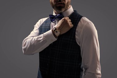 Erkek aksesuarı. Papyonlu beyefendi lüks saat gösteriyor. Pahalı bir kol saati. Papyonlu adam ve saat. Zarif saat aksesuarı. Zaman doldu. Gri renkte soyutlanmış zarif beyefendi..