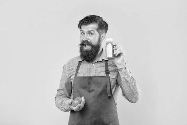 Happy man in apron holding limes and juice bottle yellow background, juicery.