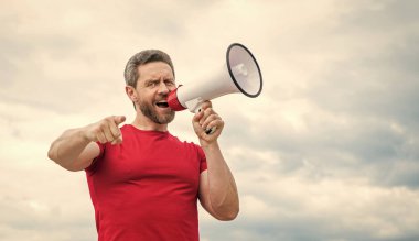 Kırmızı gömlekli adam arka planda hoparlörden bağır. işaret parmağı.