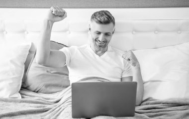 successful mature man working on laptop in bed.
