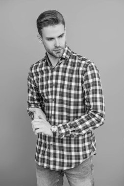 Gündelik kareli gömlekli yakışıklı genç beyaz adam, gri renkte, traşsız ve modaya uygun saç stiline sahip..