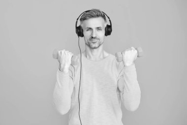 Halterli ve dambılı bir sporcu. Müzikli spor salonu. Spor salonu. Egzersiz müziği. Güçlü sporcu adam seni. Olgun bir adam mavi üzerine izole edilmiş spor eğitimi yapar. Kişisel sporlar.