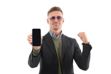 İş uygulamasının reklamı. Olgun iş adamı telefon ekranını sunuyor. İş adamı, telefonun beyazda izole olduğunu gösteriyor. Adam yeni iş telefonu uygulamasını gösteriyor. Başarıyı ifade etmek. Ürünü sunuyorum..