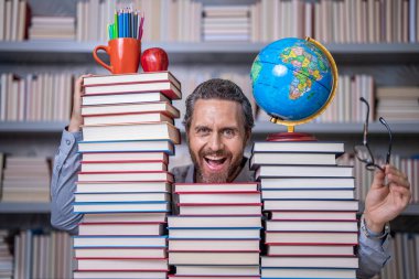 Adam kitap kurdu bilgi topluyor. Öğretmenler ve bilgi günü. Zeki öğretmen. Sınıftaki kitap kurdu adam. Kitap edebiyatı öğretmeni. Okul kütüphanesinde eğitim. Eleştirel düşünme için okuma.