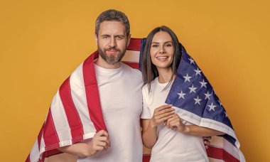 Öğrenci bir çift Amerikan bayrağıyla gururla poz veriyor. Amerikan bayrağı taşıyan çiftlerin vatanseverliği. Bayrağa sarılı Amerikalı ruh çifti kutluyoruz. Bayrağı olan Amerikalı çift..