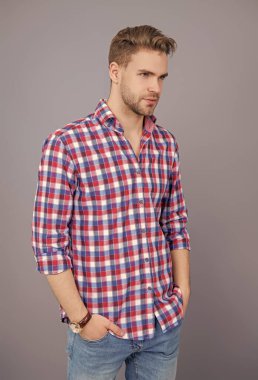 Sıradan gömlekli bir adamın portresi. Gri üzerinde kollarını çapraz tutuyor. Tıraşsız erkek derisi. Erkek güzelliği ve saç stili. Gündelik giyinen milenyum adamı. Yakışıklı genç adam. Yakışıklı adam..