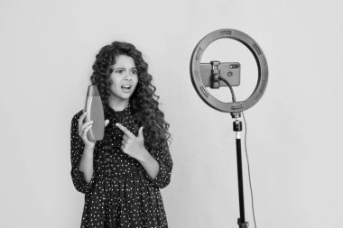 Uzun kıvırcık saçlı çocuk, blog için şampuanı işaret eden video yapıyor..