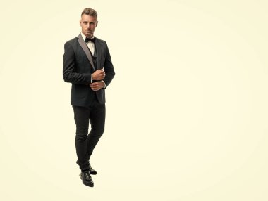 Beyaz arka planda izole edilmiş smokinli, beyaz papyonlu beyaz bir adam. tam uzunluk.