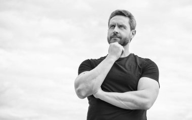 pondering man in red shirt outdoor on sky background.
