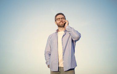 business communication of man talk on phone. man talking on smartphone. man communication talk on sky background.