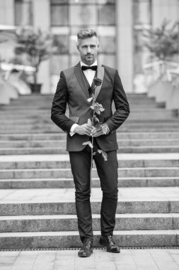 Özel bir durum için. Özel durumlar için gül taşıyan yetişkin bir adam. Smokinli adam özel bir gün için dışarı çıktı..