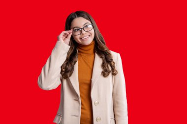 Sonbahar stil kızı. Moda ve şık bir öğrenci kız gülümsüyor. Gençler için sonbahar moda tarzı. Sonbahar modası. Sonbahar montlu kız öğrenci kırmızıda izole edilmiş. Genç kız gözlük takıyor, reklam yapıyor..