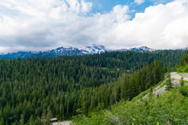 Bulutlu gökyüzü ile dağlık bir manzara. Yeşil Tepe Dağı manzaralı. Göz kamaştırıcı doğal manzara. Kozalaklı orman ve yeşil yamaçlı vahşi dağda yaz günü. Çayırlı dağ manzarası.
