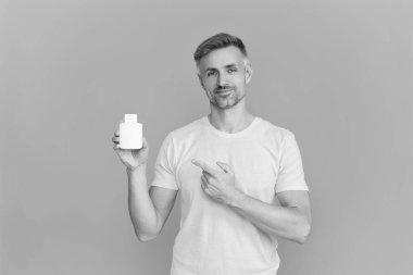 Maviye izole edilmiş multivitamin ve vitamin takviyesi veya ilaç sunan olgun bir adam..