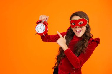 Parti maskeli neşeli genç kız saati işaret ediyor. Parti sonrası eve geç gelen bir kız. Tatil eğlencesi bitti. Geri sayım. Geç kalan kız turuncudan izole edilmiş. Geç saatte. Parti geri sayımı.