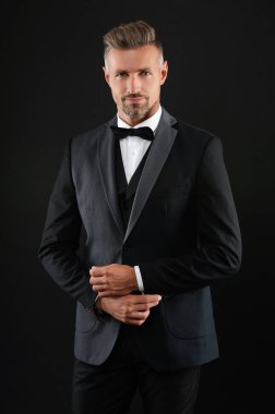 Erkek giyim tarzı. Şık smokin papyonu. Resmi etkinlikte zengin bir iş adamı. Zengin ısmarlama smokinli adam. Siyah takım elbiseli smokinli adam izole edilmiş. Resmi erkek giyim sektöründe başarılı bir adam. Damadın smokin tarzı vardır..