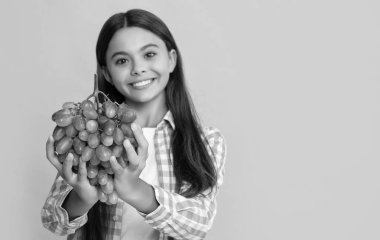 Sarı arka planda olgun üzümlü mutlu çocuk..