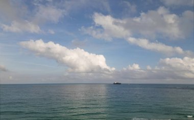 Bulutlu bir hava ve yaz tatilinde deniz manzaralı bir gemi. Deniz ufkuyla gökyüzü. Deniz doğasına sakin bir ufuk açısı. Deniz manzaralı romantik yaz tatili manzarası. Deniz ufku görünümü.
