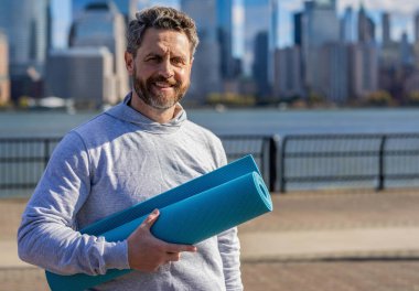 Yoga koçu. Sporcu adam antrenmana hazır. Sağlıklı bir yaşam tarzı. Spor ve spor. Eğitim için yoga minderi. New York 'ta sporcu. Manhattan 'da spor kıyafetli bir adam. Vücuduna uygun. Boşluğu kopyala.
