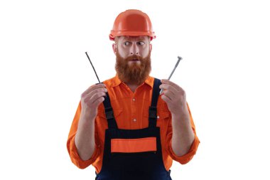 Üniformalı tamircinin çivisi var. Sakallı marangoz çivi tutar. Marangoz, çivi beyazı ile onarıyor. Tamirci. Adam çekiç çivisi tutuyor. Marangozluk tamir ve çekiç. Çekiçlemede hassasiyet.