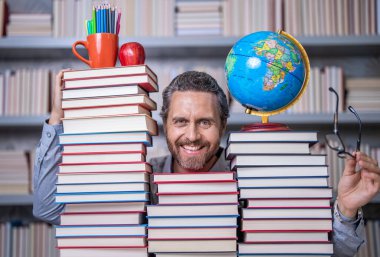 Öğretmenler ve bilgi günü. Zeki öğretmen. Sınıftaki kitap kurdu adam. Kitap edebiyatı öğretmeni. Okul kütüphanesinde eğitim. Adam kitap kurdu bilgi topluyor. Okuma alışkanlıkları.