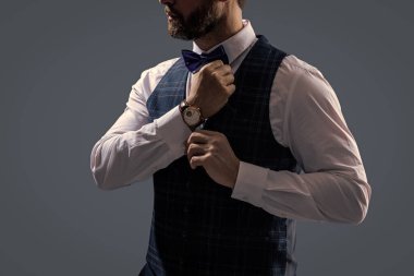 Pahalı bir kol saati. Papyonlu adam ve saat. Zarif saat aksesuarı. Zaman doldu. Gri renkte soyutlanmış zarif bir beyefendi. Erkek aksesuarı. Papyonlu beyefendi lüks saat gösteriyor. Hazırlanıyor..