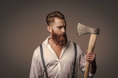 Erkek vahşeti. Antika pantolon askılı, eski tip bir gaddar adam. Askılık giymiş vahşi bir adam gride izole edilmiş. Saçları kızıl saçlı, olgun bir adam. Acımasız erkek modası. Retro saç stili.