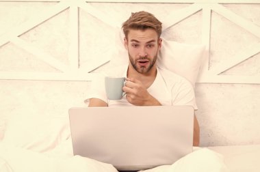 Adam yatakta yatıp dizüstü bilgisayarla internette sörf yapıyor. Bilgisayarda evden çalış. Hafta sonu işkolik. Sabah kahvesi hazır. Yatakta serbest çalışan. Milenyum adamı evde dizüstü bilgisayarda çalışıyor. Video çağrısı.