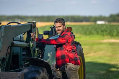 Tarım ve saha işleri. Tarladaki çiftçi dışarıda traktörle kareli gömlek giyiyor. Ekin hasadı. Tarım ekipmanları. Hasat makineli bir çiftçi. Traktörde olgun bir adam var. Traktör sürücüsü.
