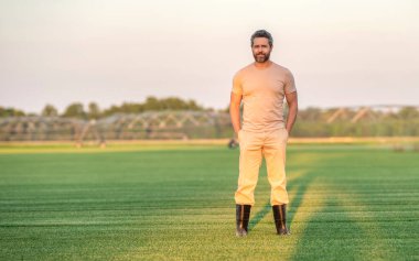 Tarım ve tarım. Sulama sisteminde tarımı sulayan bir adam. Kırsal kesimde bir çiftçi. Su püskürtme sulama tarlası. Damlatma sulama sistemi. Ekin sulama pankartı.