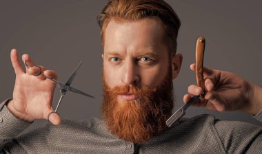 Berber adam kuaförde makas ve bıçak tutuyor. Berber dükkanı konsepti. Berber Gri Stüdyo 'da izole edilmiş. Berber dükkanında elinde makas olan bir adam. Berber dükkanındaki berber..