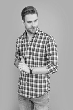 Stüdyoda gülümseyen adamın fotoğrafı. Sakalı olan beyaz bir adam. Gri arka planda kareli gömlekli yakışıklı bir adam izole edilmiş. Sıradan tarzda bir adam..
