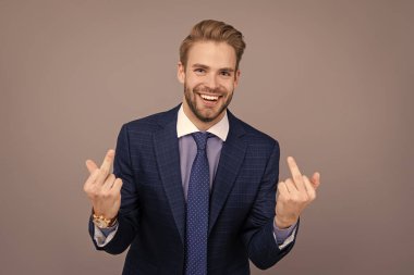 Takım elbiseli bir iş adamı, grinin üstünde münasebetsiz bir hareket gösteriyor. Orta parmağı olan kibirli bir avukat. İşadamı saldırgan davranışlar sergiliyor. Vücut dili. Kaba iş adamı orta parmağını gösterdi.