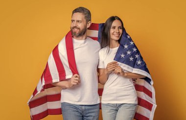 Amerikan bayrağı taşıyan çiftlerin vatanseverliği. Bayrağa sarılı Amerikalı vatansever çifti kutluyoruz. Bayrağı olan Amerikalı bir çift. Bir çift Amerikan bayrağıyla gururla poz veriyor..
