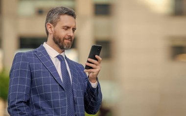 Ofis binasında telefonu olan İspanyol bir iş adamı. Telefon kullanan bir iş adamı. Şehirdeki erkek telefon konuşmaları. İş adamı telefonda konuşuyor. İş adamı ön ofiste. Sosyal ağ. Pankart.