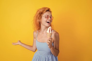 Yazın waffle külahında leziz dondurmalar. Yazın dondurma yiyen bir kız. Gözleme külahında dondurması olan mutlu genç bir kadın sarıya izole edilmiş. Kornet dondurmalı bir kadın. Şarkı söylemek ve eğlenmek..