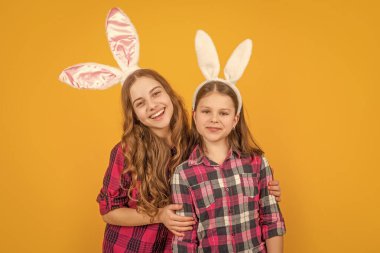 Sarı arka planda tavşan kulaklı mutlu Paskalya çocukları.