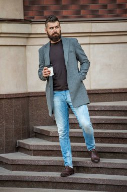 Günlük stil rutini. Sakallı adam şehir caddesinde kahve içiyor. Sokakta elinde kahve tutan yakışıklı bir adam. İş molası. Sabah kahvesi içen adam. Kahve molası. Binadan çıkıyorum..