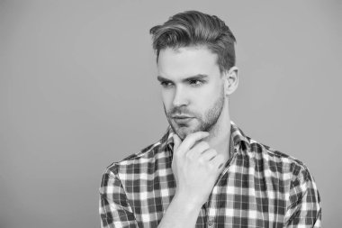 Yakışıklı genç adam. Sıradan gömlekli bir adamın portresi. Gri üzerinde kollarını çapraz tutuyor. Tıraşsız erkek derisi. Erkek güzelliği ve saç stili. Gündelik giyinen milenyum adamı. Seksi portre..