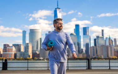 Manhattan 'da spor kıyafetli bir adam. Vücuduna uygun. Yoga koçu. Sporcu adam antrenmana hazır. Sağlıklı bir yaşam tarzı. Spor ve spor. Eğitim için yoga minderi. New York 'ta sporcu.